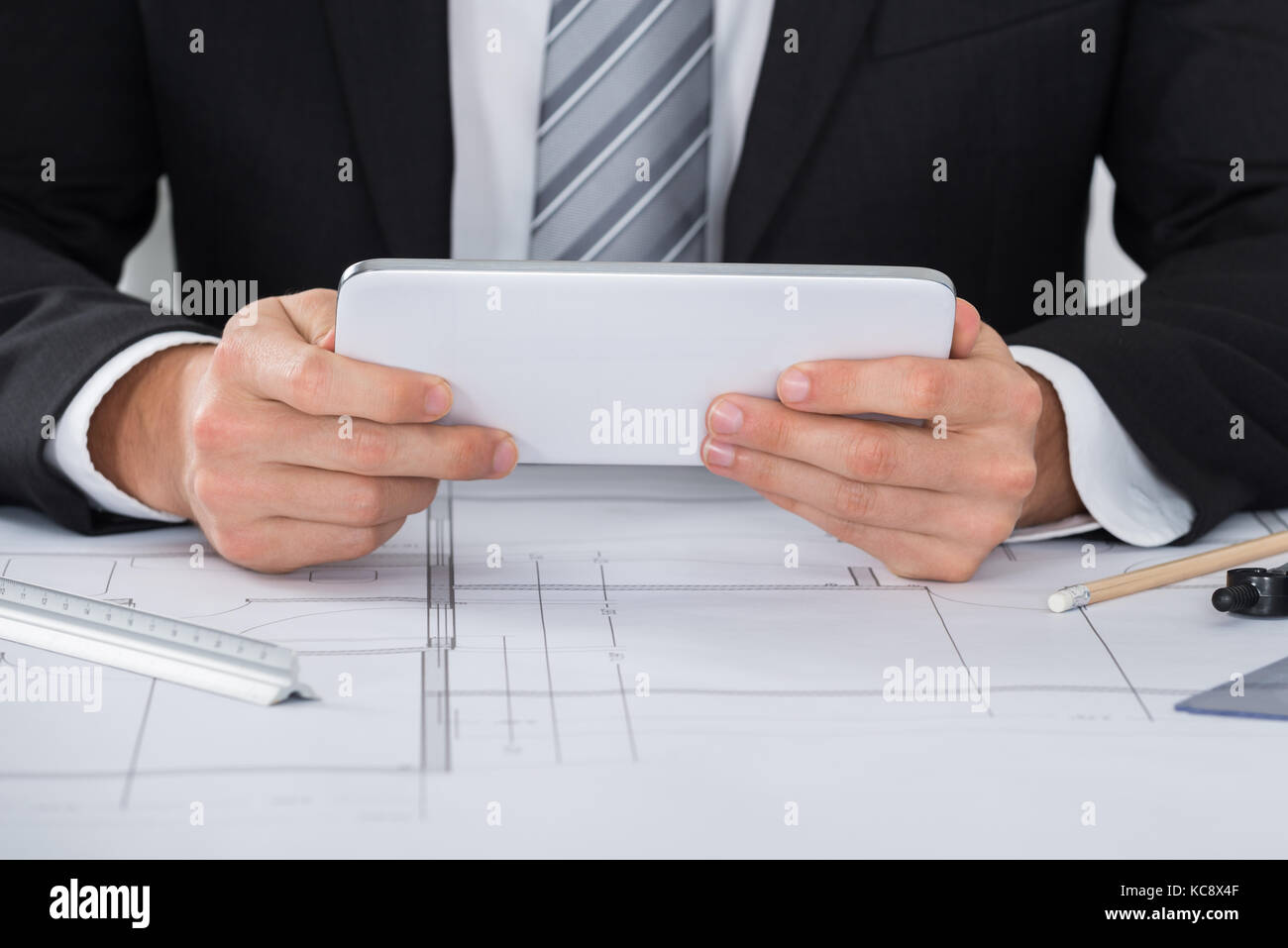 Close-up Of Male Architecture Using Digital Tablet Over Blueprint Stock Photo
