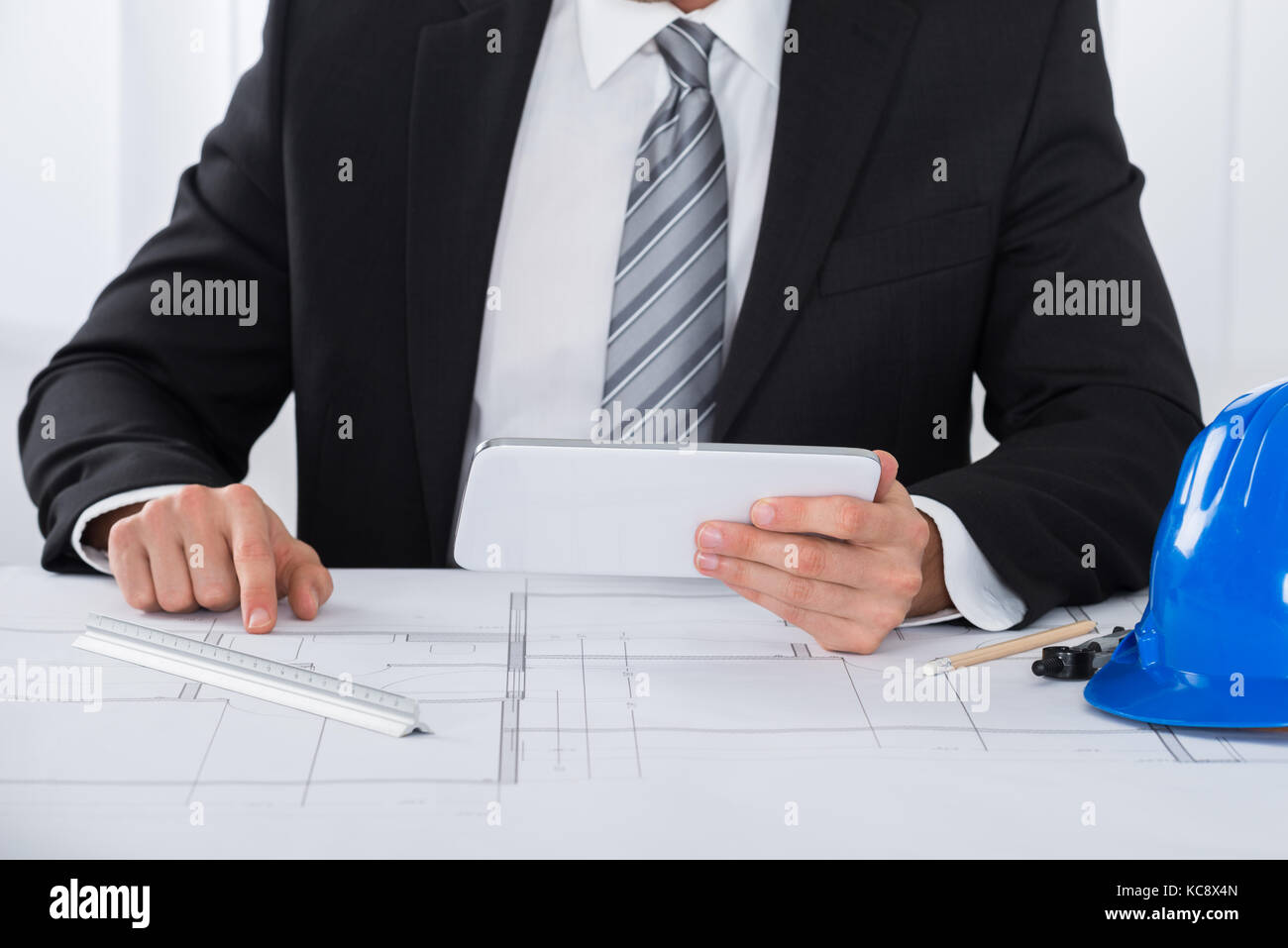 Close-up Of Male Architecture Using Digital Tablet Over Blueprint Stock Photo
