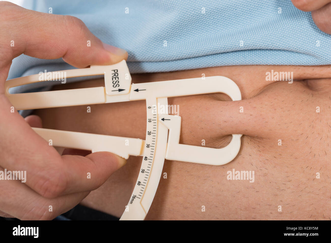 Close-up Of Young Man Measuring Fats With Caliper Stock Photo