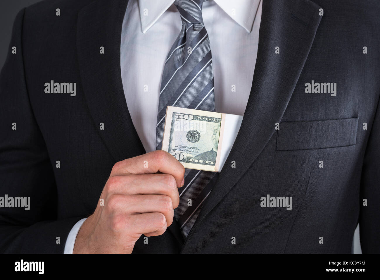 Close-up Of Businessman Hand Putting Bribe In Suit Pocket Stock Photo
