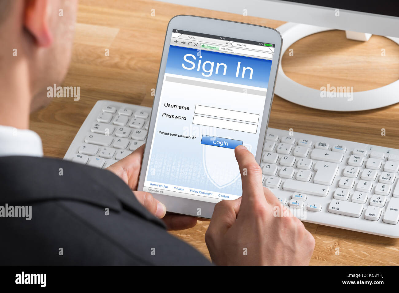 Close-up Of Young Businessman Signing Into Website Using Digital Tablet At Computer Desk Stock Photo
