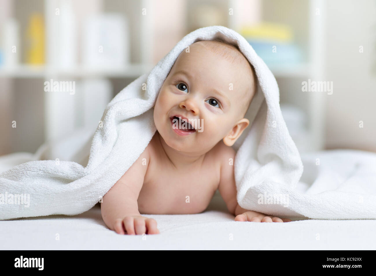 little baby boy lies on belly smiling under white towel Stock Photo Alamy
