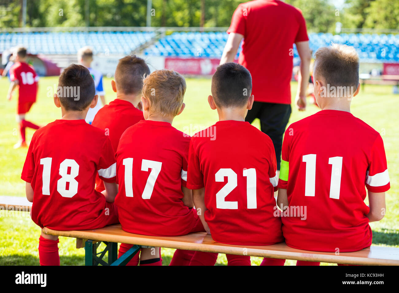 Kids Soccer Team. Youth Football Players with Soccer Coach. Young Substitute Player Sitting on Wooden Bench. Stock Photo