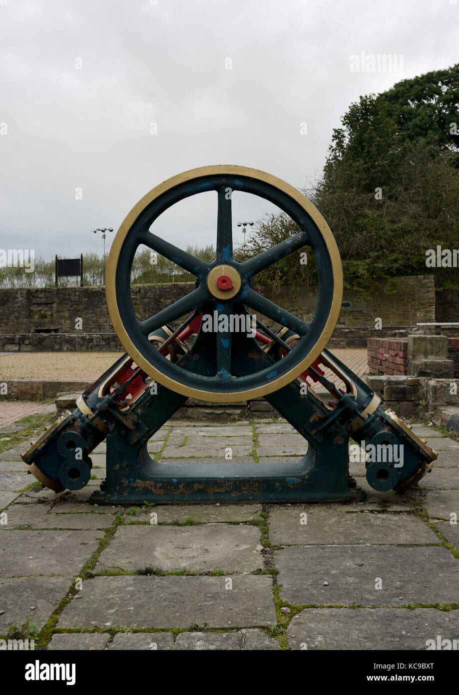 Six spoke metal wheel on old mill machinery fixed to flagstones in burrs country park bury lancashire uk Stock Photo