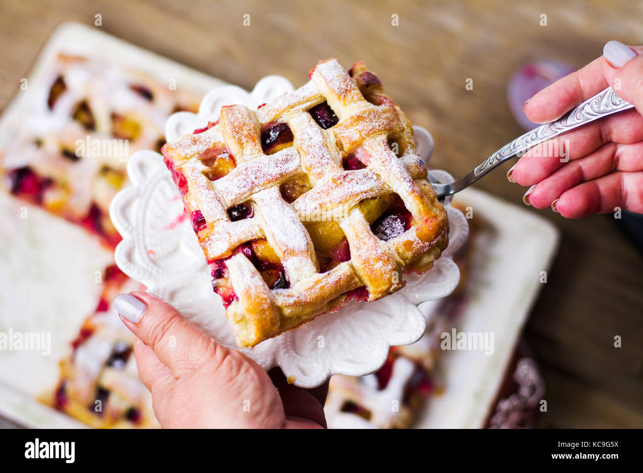 Woman serving sweet fruit pie slice on a plate Stock Photo