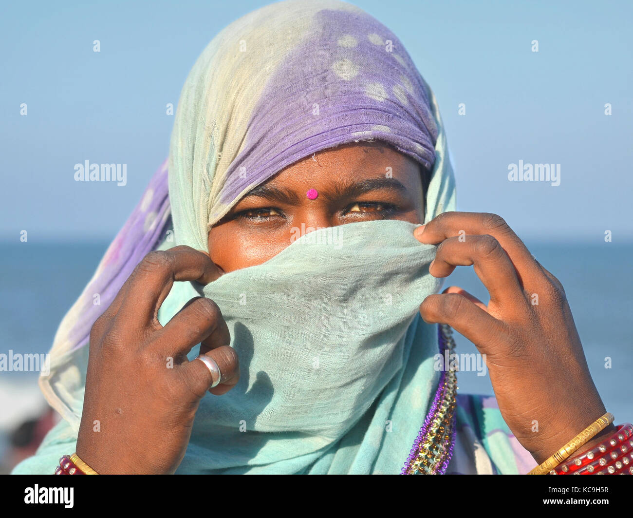 Young Indian souvenir saleswoman, covering her nose and mouth with a blue dust veil Stock Photo
