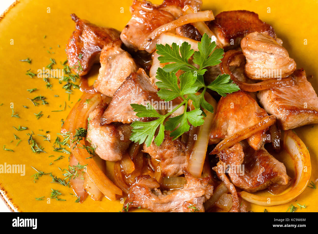 Fried meat with onions on plate Stock Photo