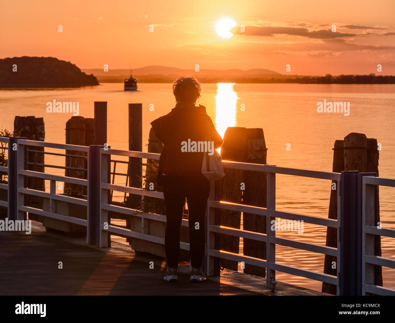 Silhouette of a woman at sunset with a boat in the background Stock ...
