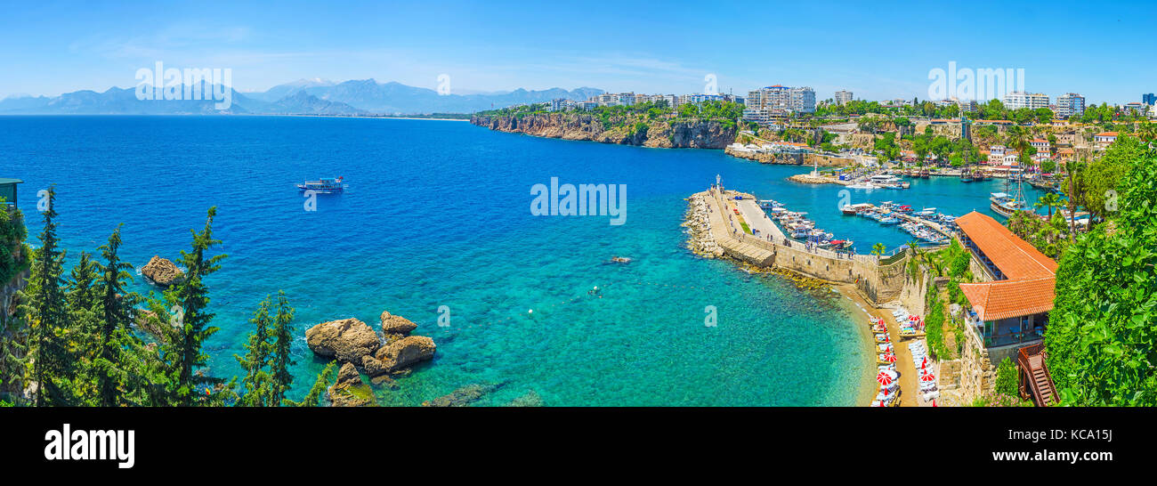 Panorama of Antalya coast from the tall cliff with Mermerli beach, Pier of old port, modern hotels and Taurus mountains on background, Turkey. Stock Photo