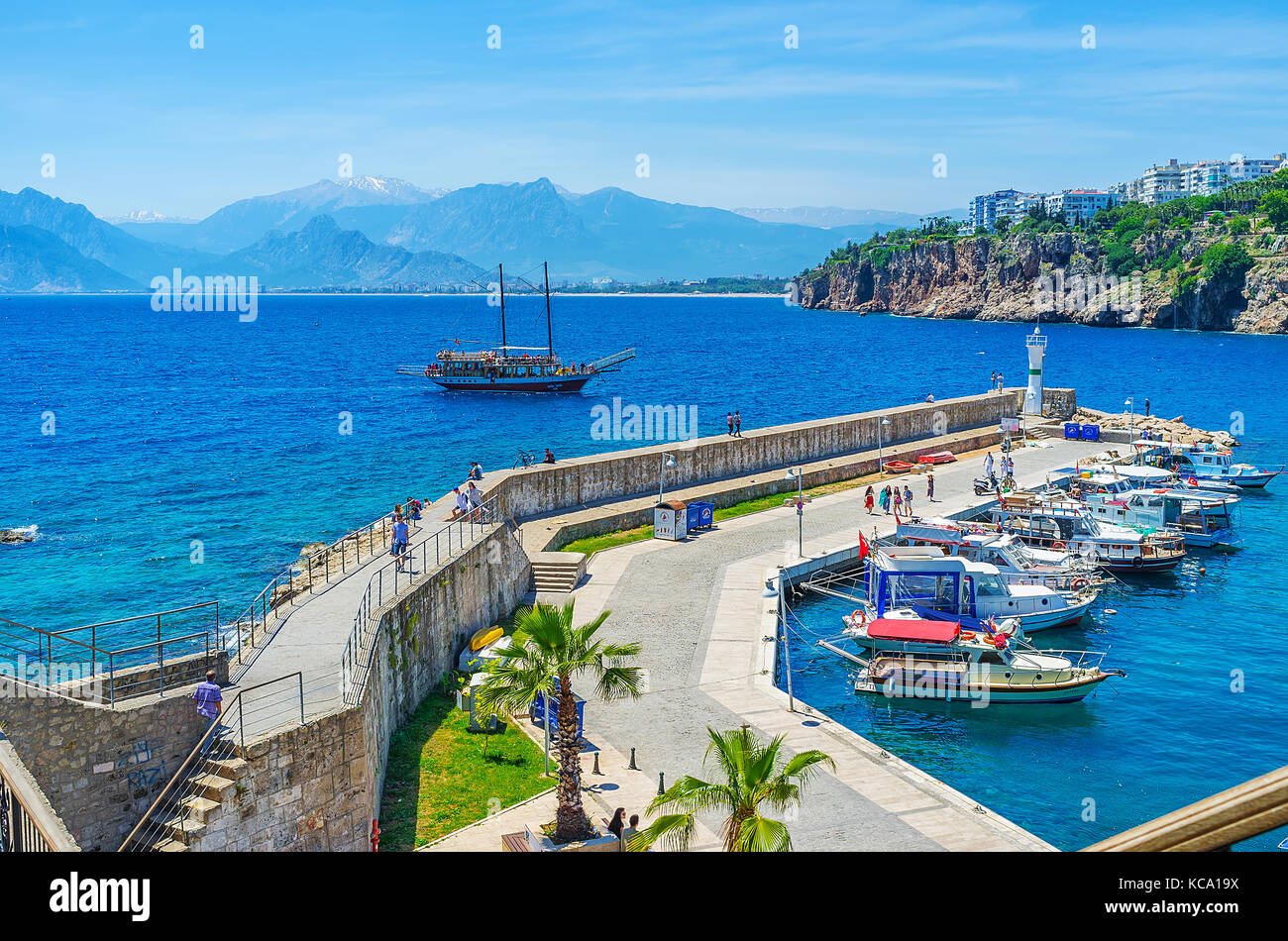 ANTALYA, TURKEY - MAY 12, 2017: The pier and lighthouse of old port in Kaleici with sailing yacht and huge mountain range on the background, on May 12 Stock Photo