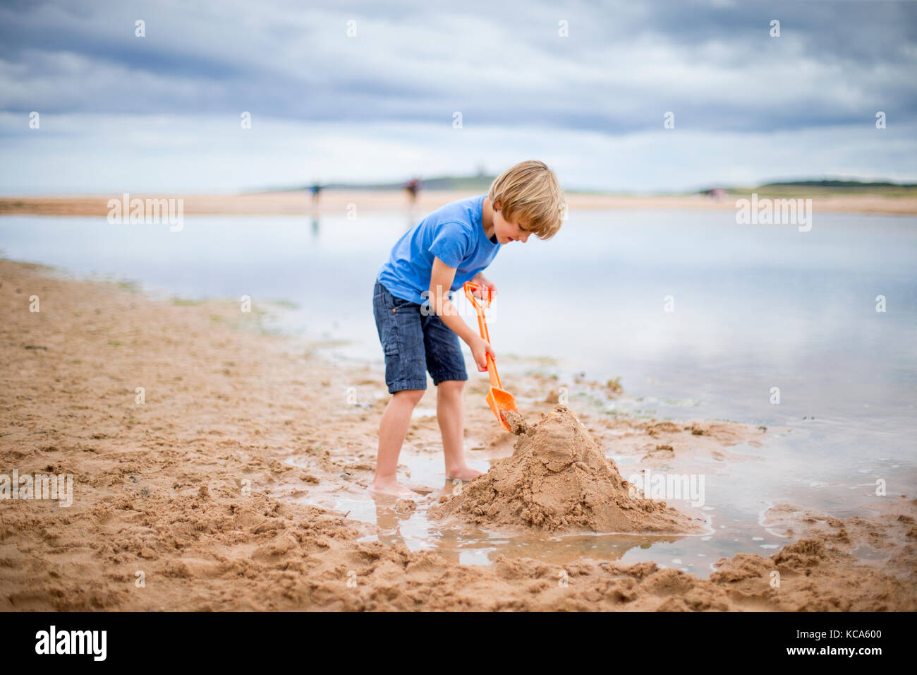 Мальчик на пляже строит замок