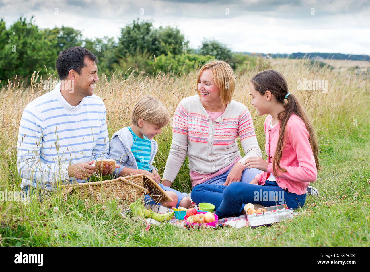 A family of four are sat on the sand dunes having a picnic Stock Photo