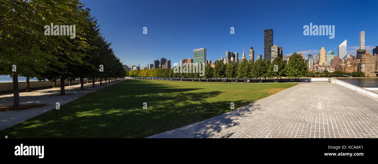 Panoramic Summer view of Franklin D. Rosevelt Four Freedoms Park lawn with the skyscrapers of Manhattan Midtown East. Roosevelt Island, New York City Stock Photo