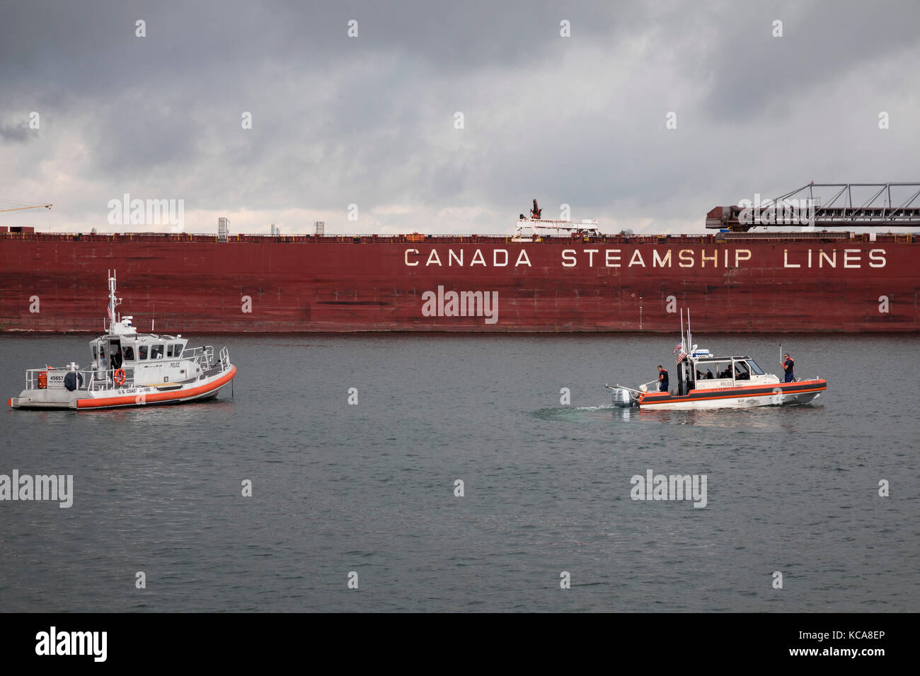 Sault Ste Marie, Michigan - U.S Coast Guard boats near the CSL Laurentien, a Great Lakes bulk cargo freighter, on the St. Mary's River, just below the Stock Photo