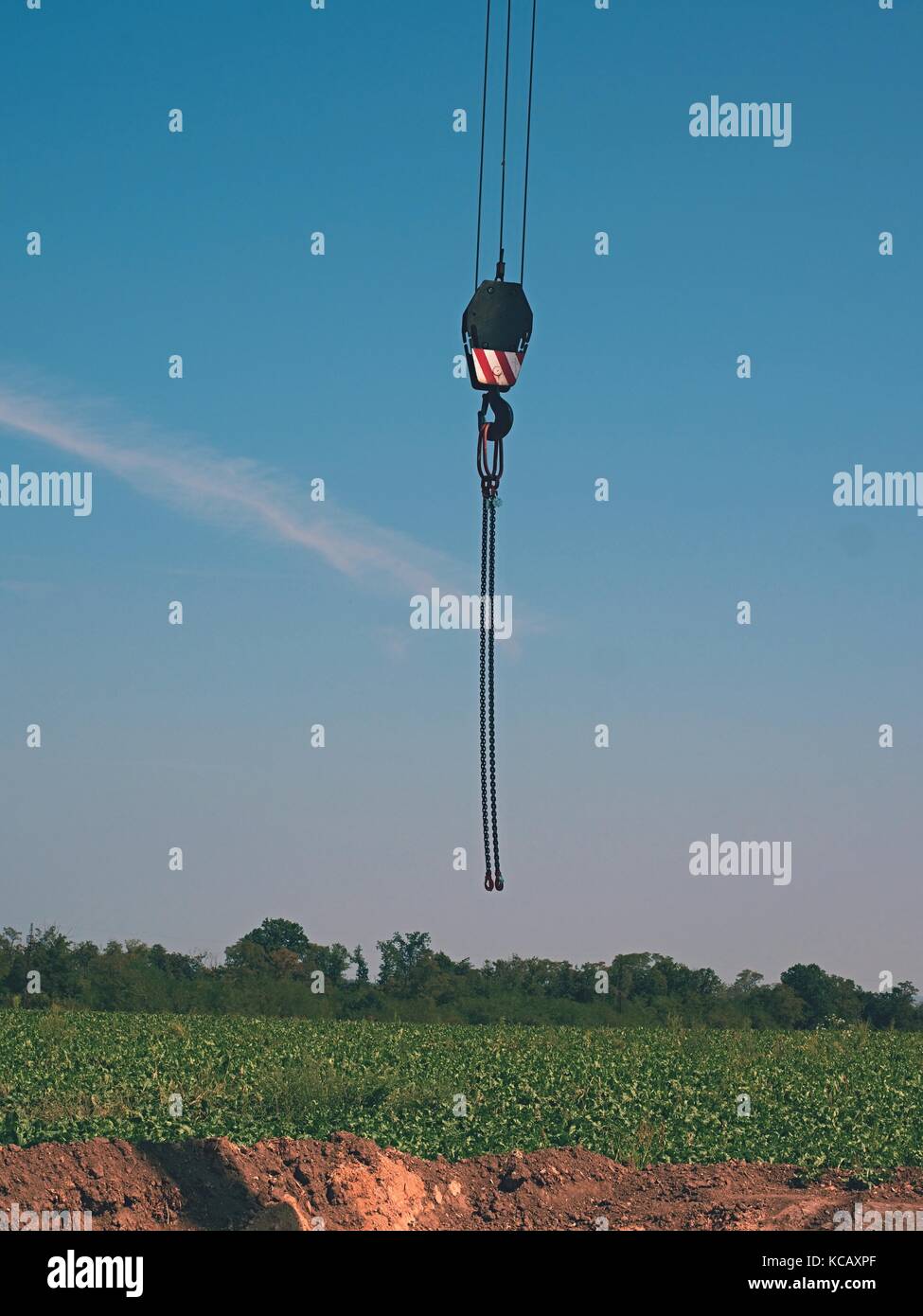 Empty hook of a large crane in outdoor building action. Empty hol diged in the field, blue sky in backgrround Stock Photo