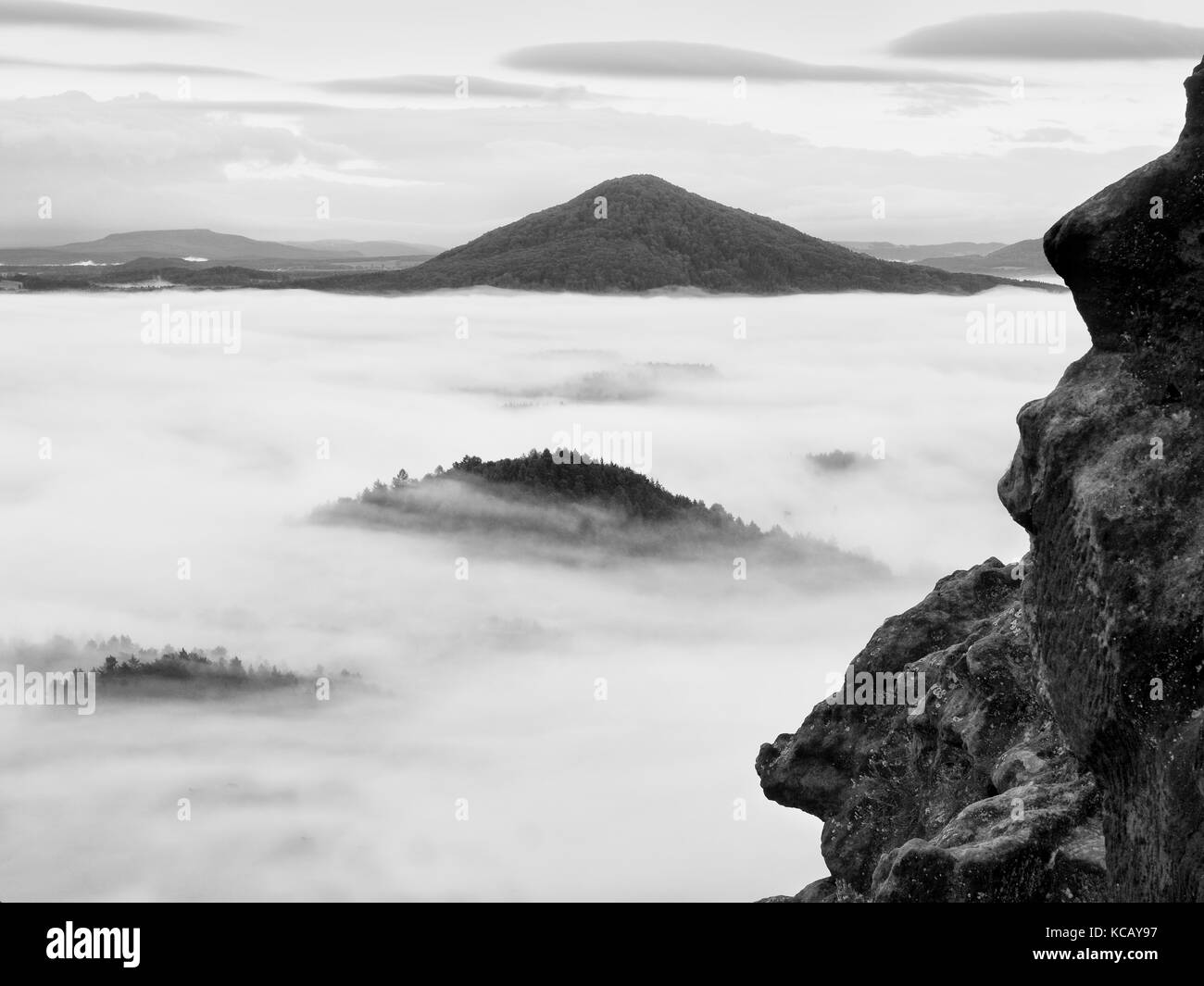 Spring misty landscape. Early morning ina beautiful mountains of Bohemian-Saxony Switzerland. Peaks of hills increased from heavy creamy fog. Stock Photo