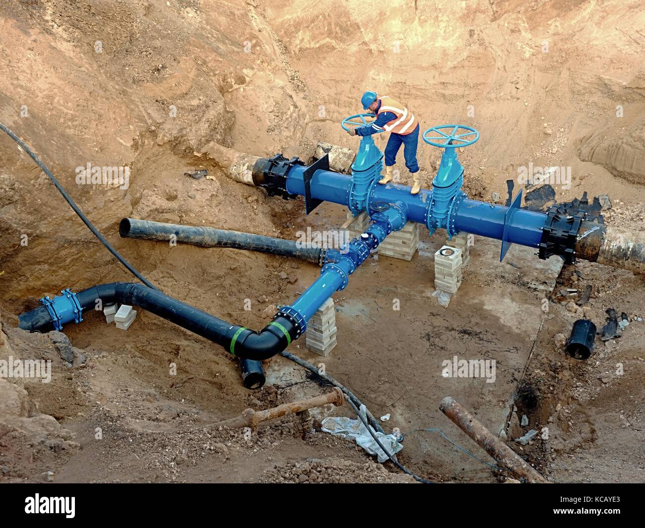 Technical expert open gate valve on 500mm drink water pipes joined with new black Flexible Joint Units into old pipeline system. Control check o Stock Photo