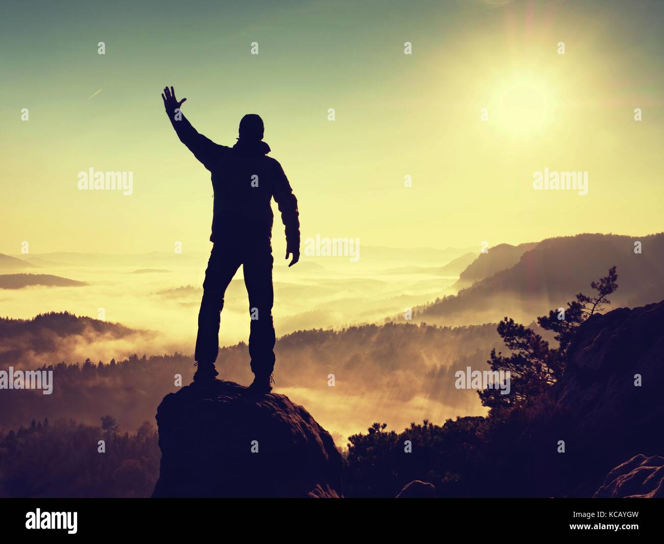 The man standing high on cliff. Hiker climbed up to rocky peak and