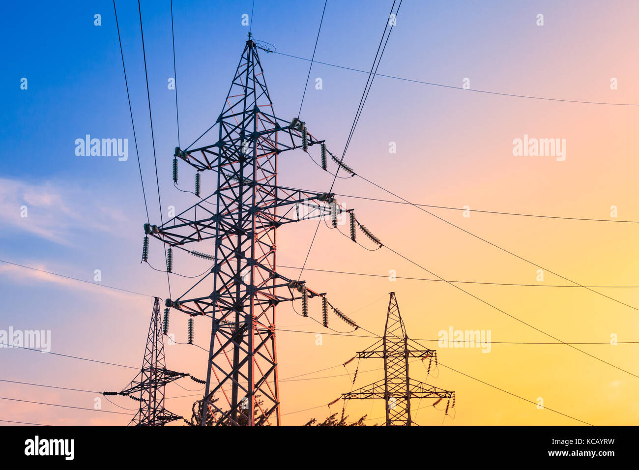 High voltage electricity pylons and transmission power lines on the blue sky background. Stock Photo