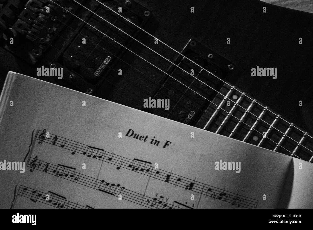 an electric guitar instrument and a piece of music sheet and notes book black and white Stock Photo