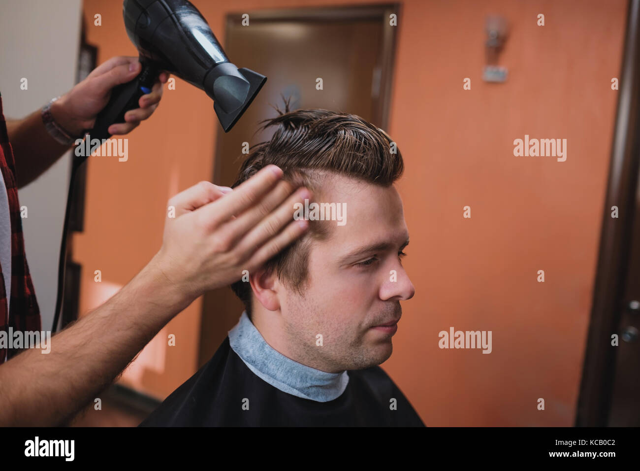 Barber using hair dryer and comb Stock Photo - Alamy