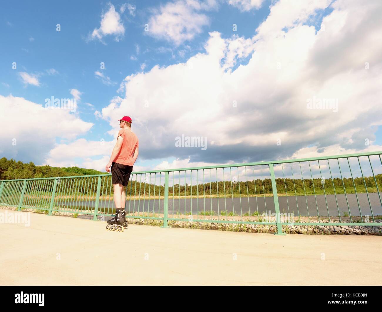 Rear view to inline skater in red tshirt and black pants skating on