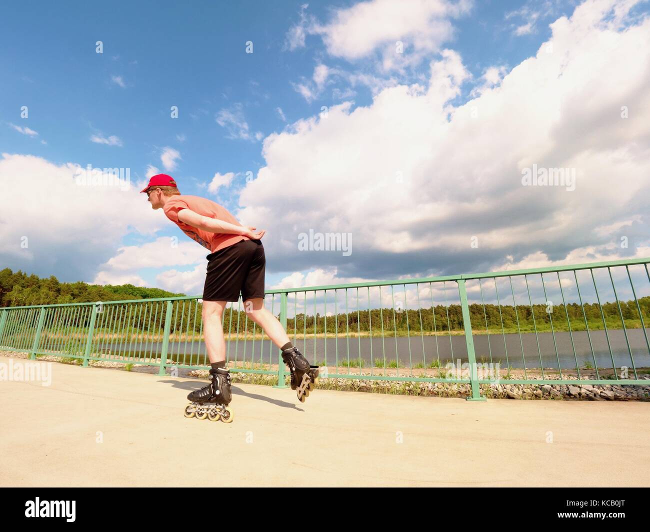 Rear view to inline skater in red tshirt and black pants skating on