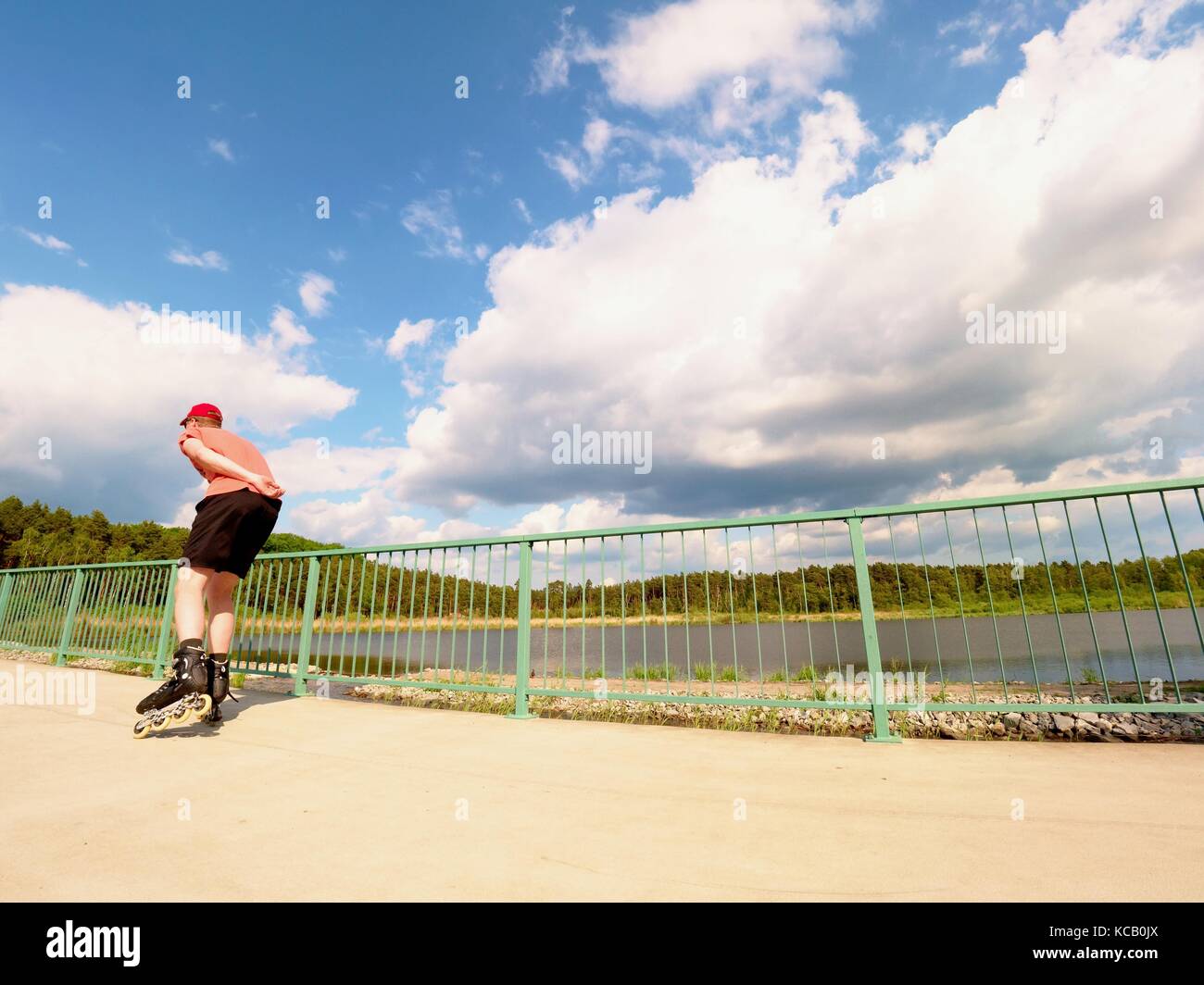 Rear view to inline skater in red tshirt and black pants skating on