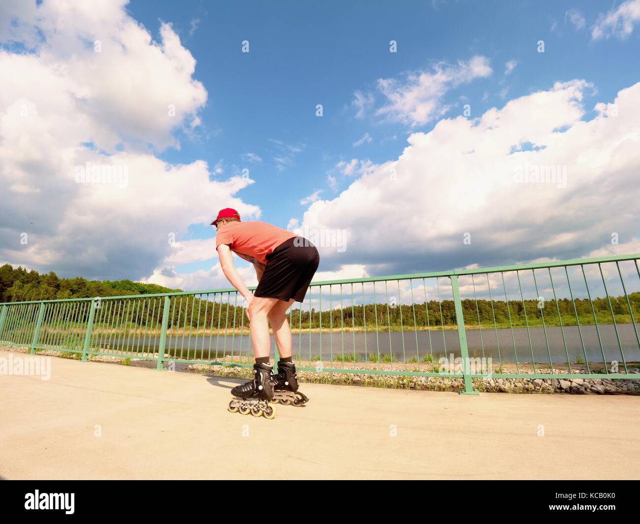 Rear view to inline skater in red tshirt and black pants skating on