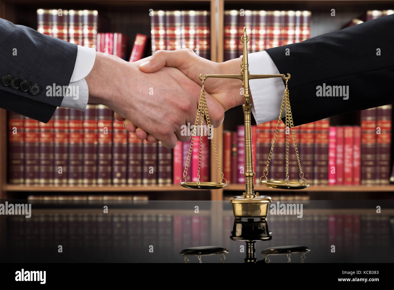 Close-up Of A Justice Scale With Judge And Client Shaking Hands In A Courtroom Stock Photo