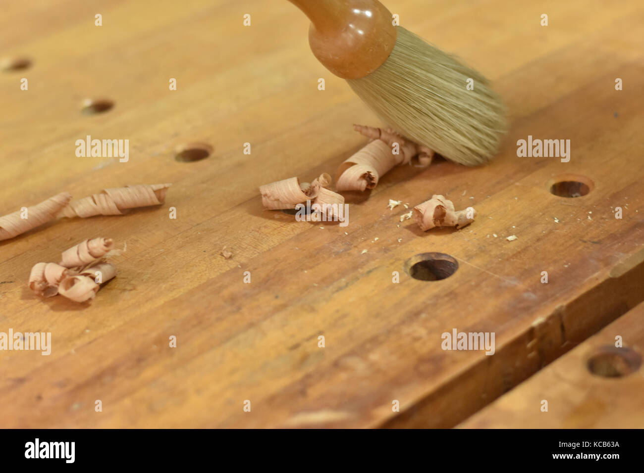 Removing wood shavings from a hard maple workbench with a dust brush. Stock Photo