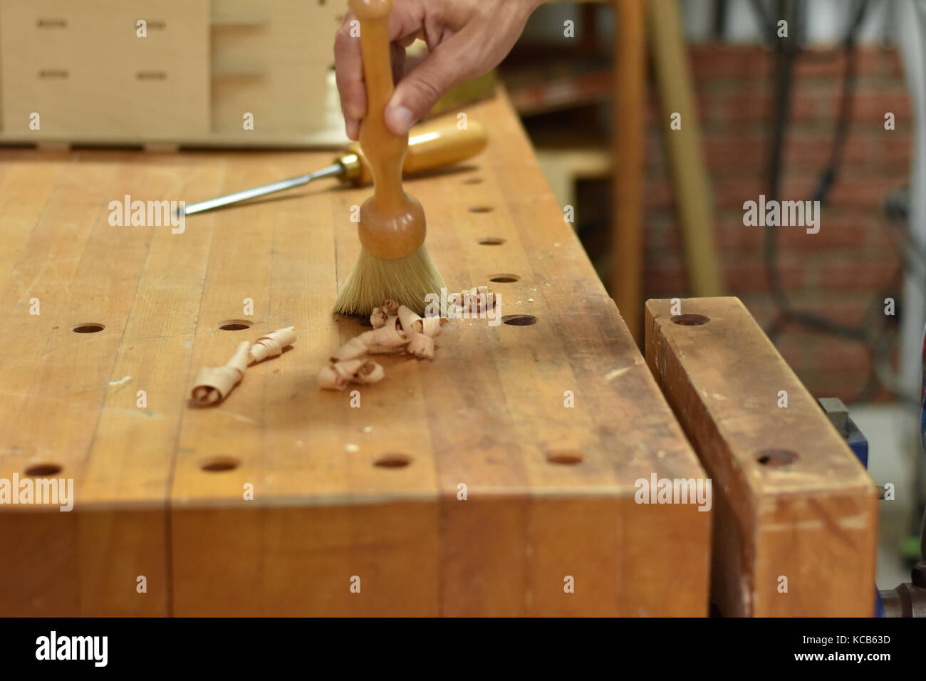 Removing wood shavings from a hard maple workbench with a dust brush. Stock Photo