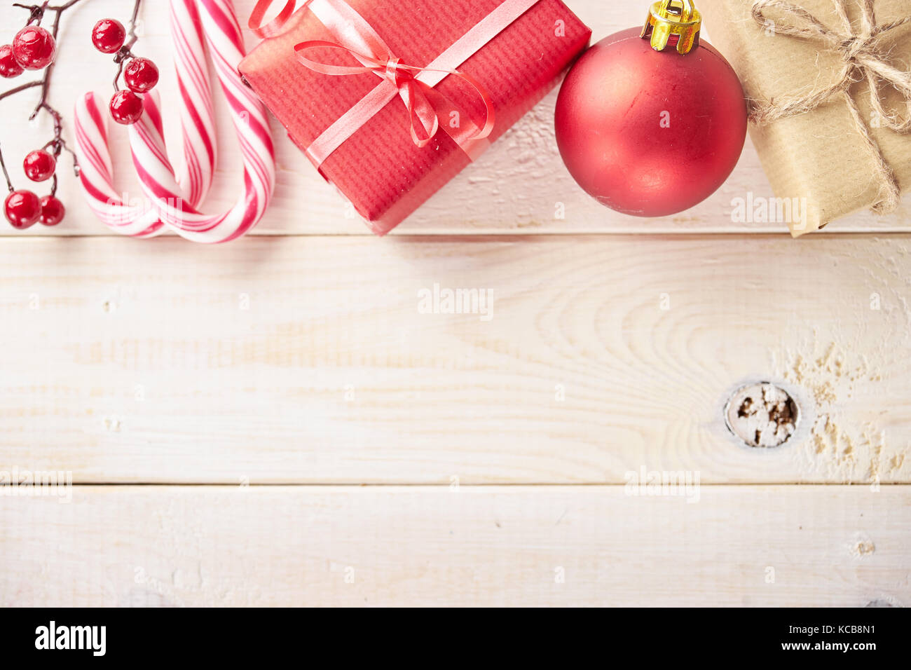 Top view of red and white Christmas decorations and cane candies on wooden desk. Copy space. Stock Photo