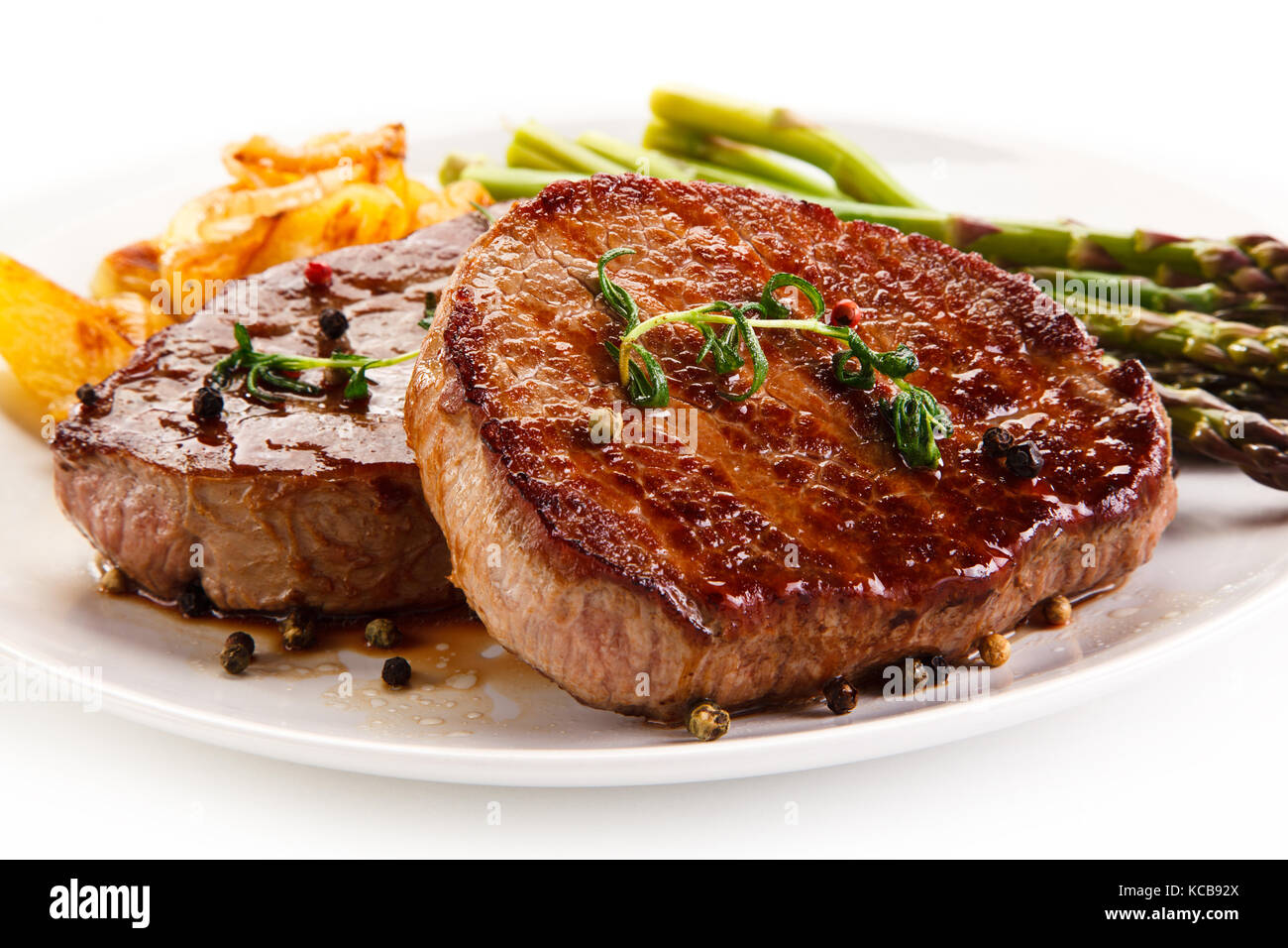 Grilled beef steaks,chips and asparagus on white background Stock Photo
