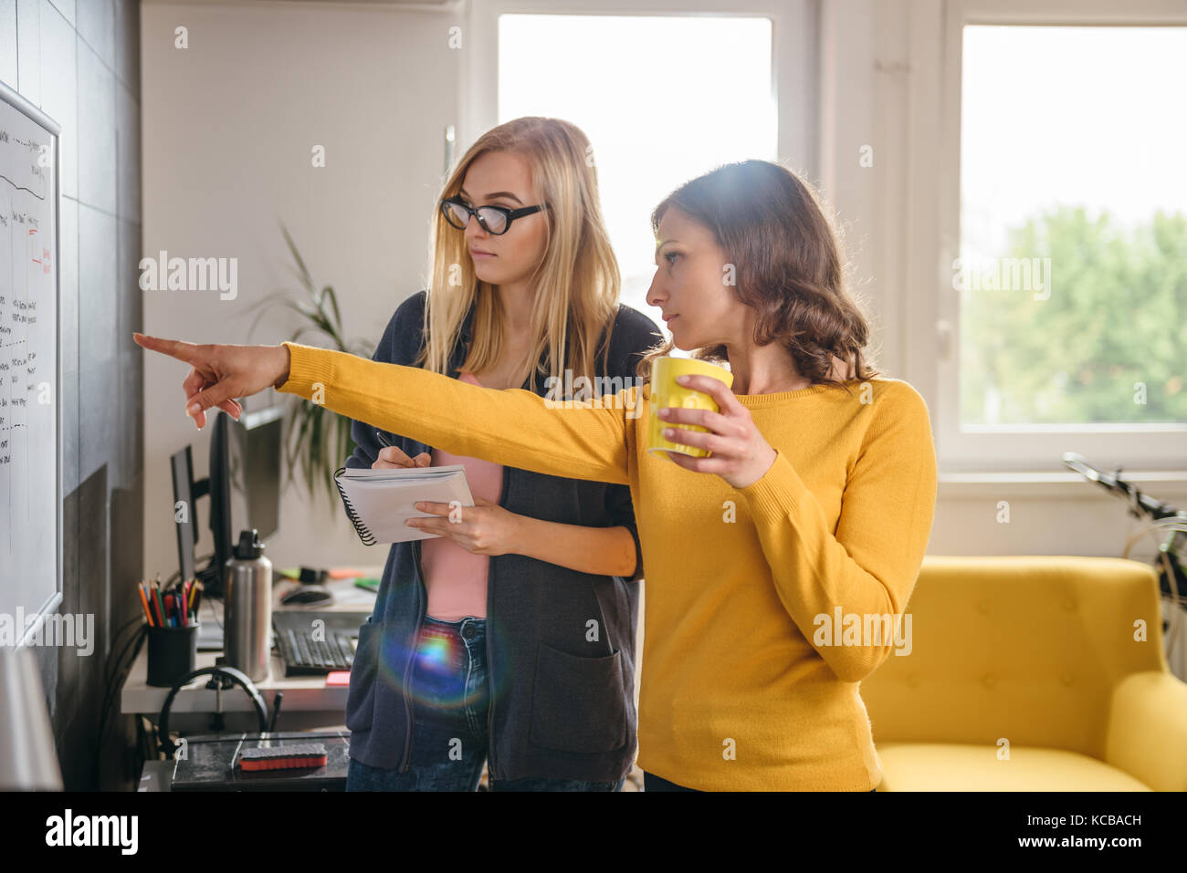 Two business woman discussing in front of the whiteboard in the office Stock Photo