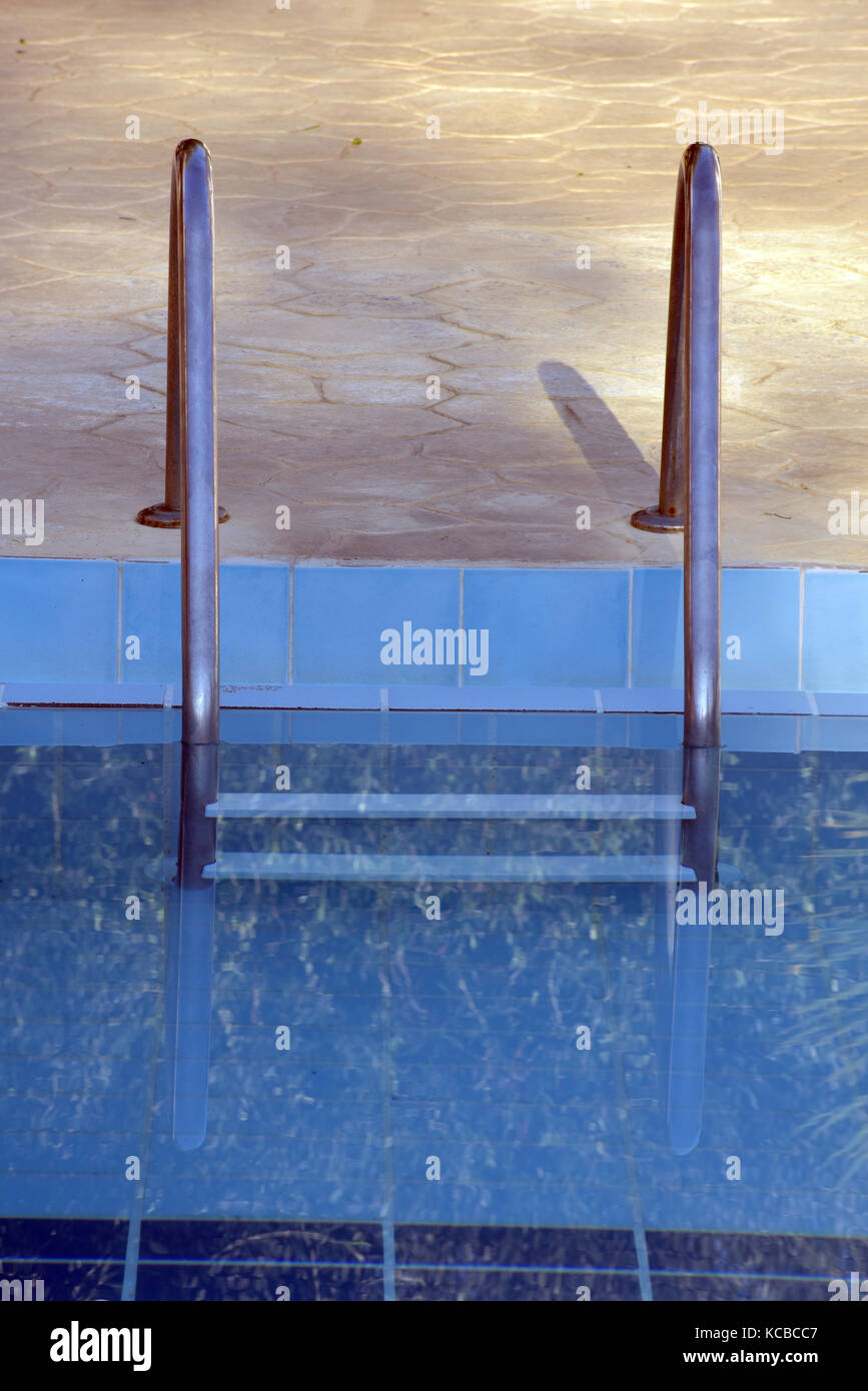 a chrome ladder into a swimming pool with blue water at a luxury hotel ...