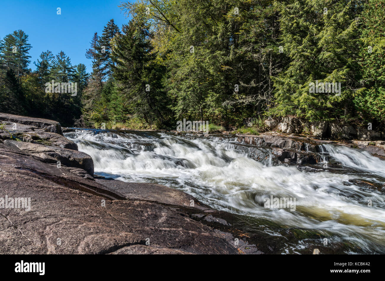 rapid water flowing over rock ledges on the AuSable river Stock Photo