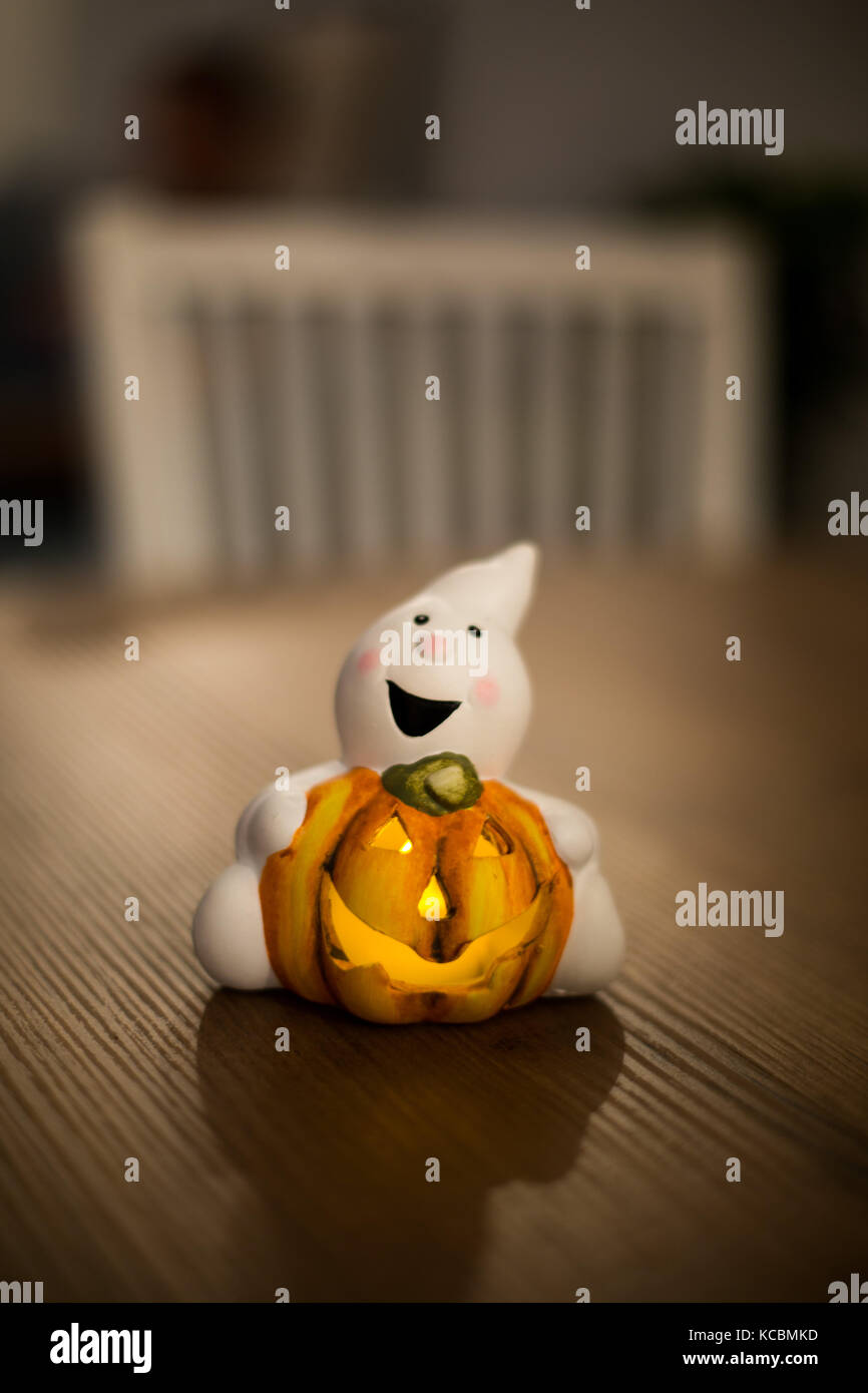 Ghost holding pumpkin on the wooden table at halloween night Stock Photo