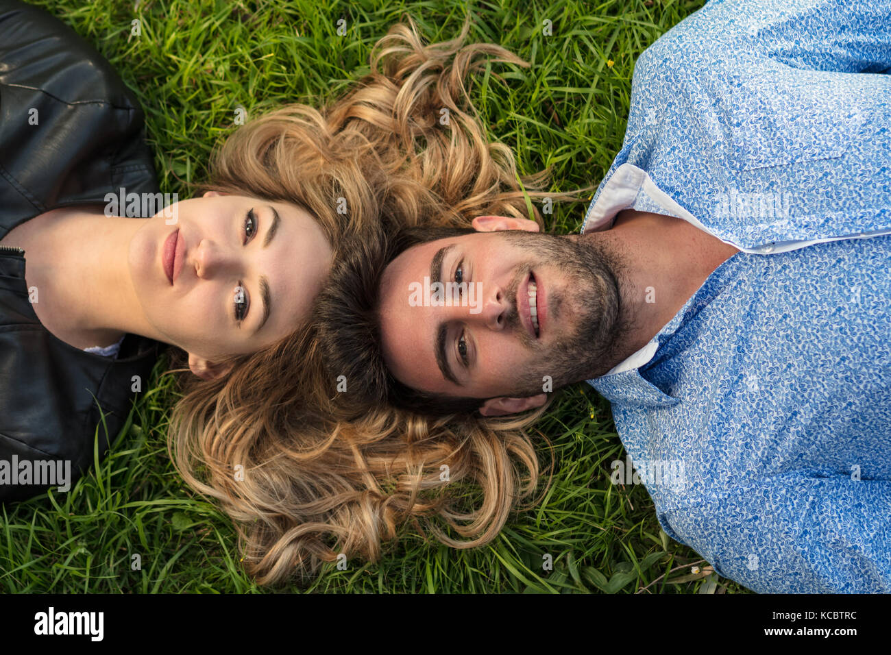 Top view of two friends smiling while looking towards the sky as they laying at the grass. Stock Photo