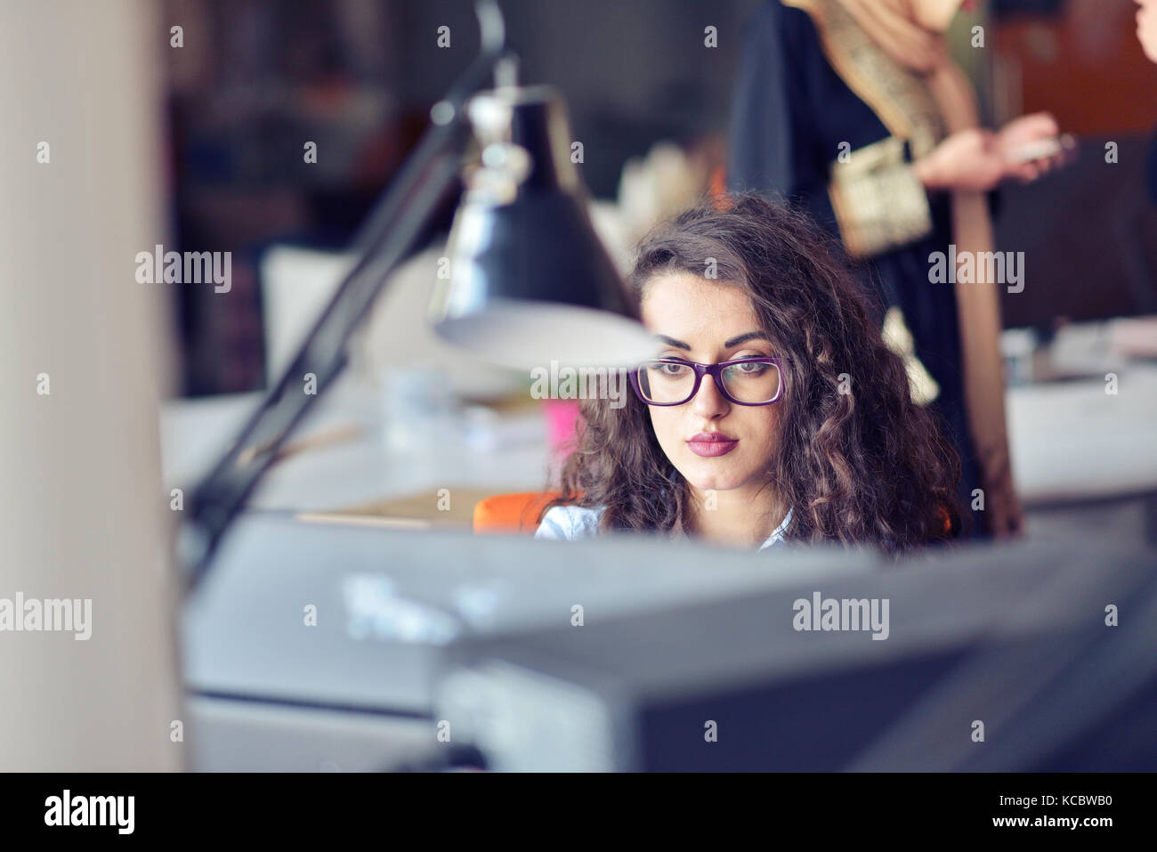 Portrait of smiling pretty young business woman in glasses sitting on ...