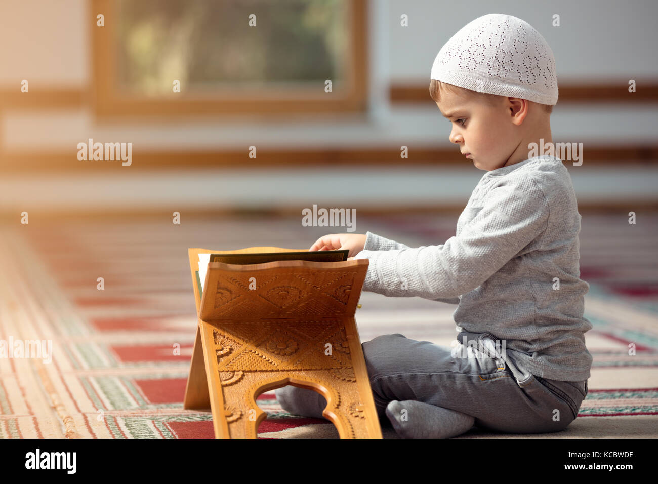 The Muslim child prays in the mosque, the little boy prays to God, Peace and love in the holy month of Ramadan. Stock Photo