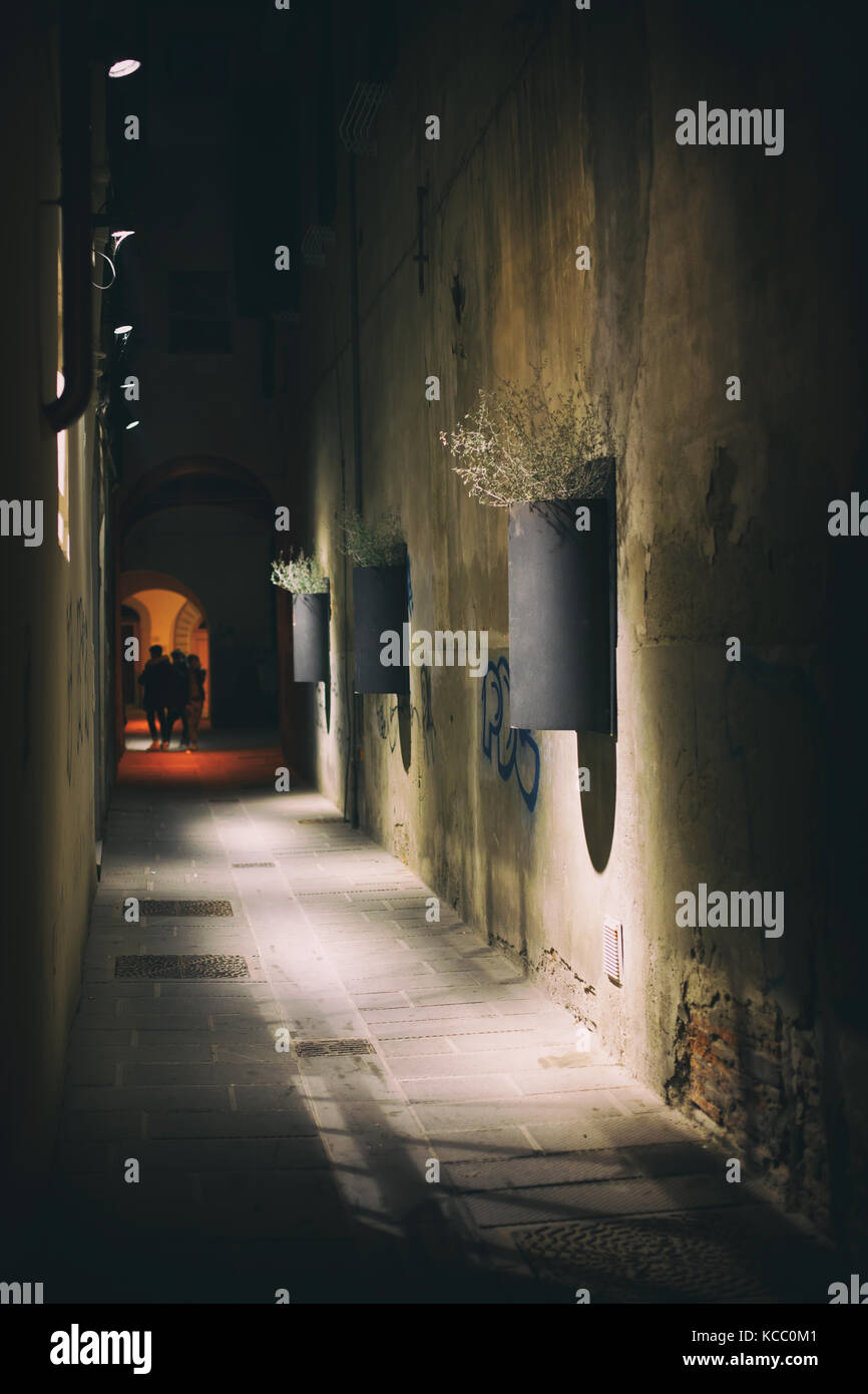 Night photo of a city alley with young teenagers in the darkness. Stock Photo