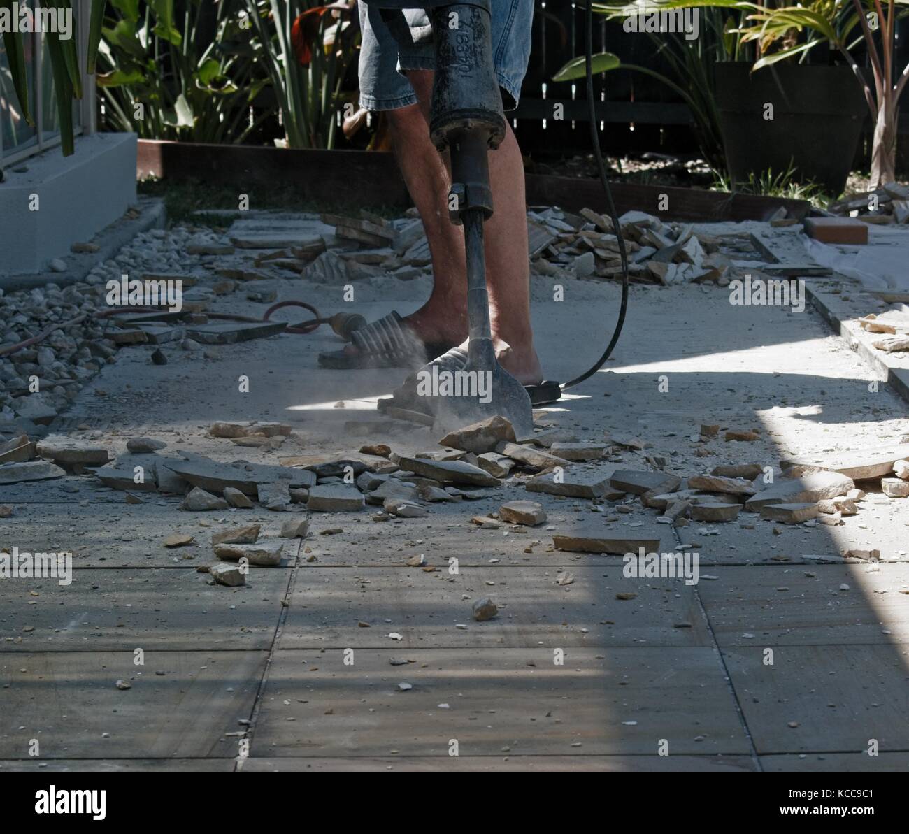 A worker is removing sandstone tiles with a jackhammer Stock Photo