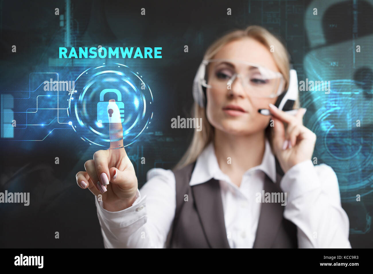 Young businesswoman working in virtual glasses, select the icon RANSOMWARE on the virtual display Stock Photo