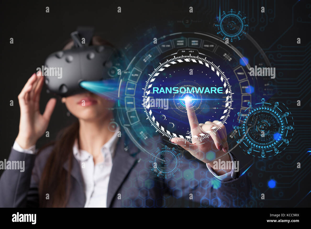 Young businesswoman working in virtual glasses, select the icon RANSOMWARE on the virtual display Stock Photo