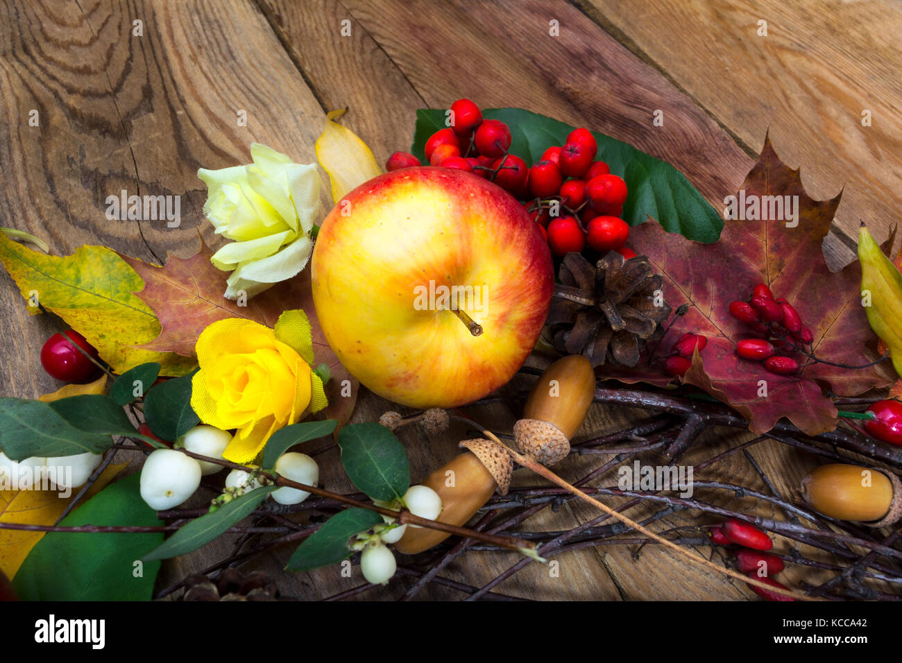 Thanksgiving background with apple, acorns and yellow roses on the wooden table Stock Photo