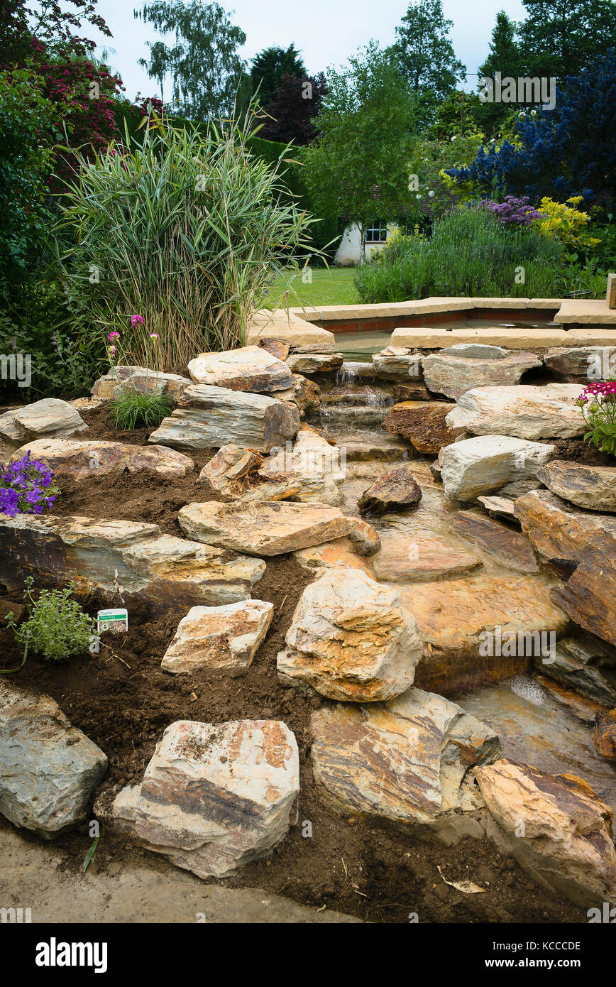 Planting a new rock garden after installing a hand-built natural stone waterfall in an English garden in UK Stock Photo