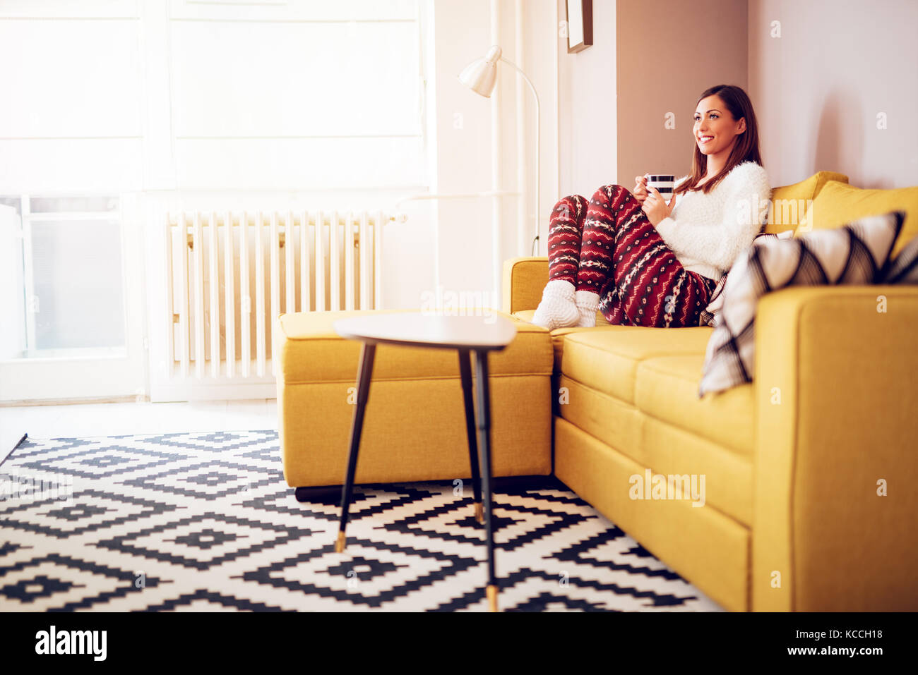 Beautiful young smiling woman relaxing on sofa at living room while ...