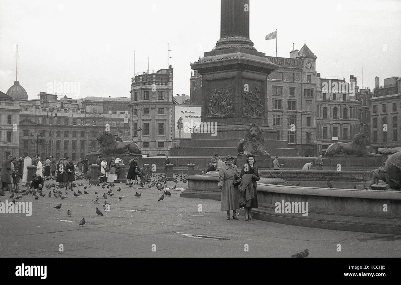 1944, historical picture of some visitors to the famous Trafalgar Square in Central London, England, UK. People feeding the pigeons by the base of Nelson's Column. Stock Photo