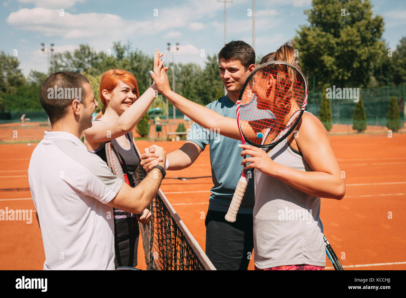Four young friends giving a high-five after tennis training. Selective focus. Stock Photo